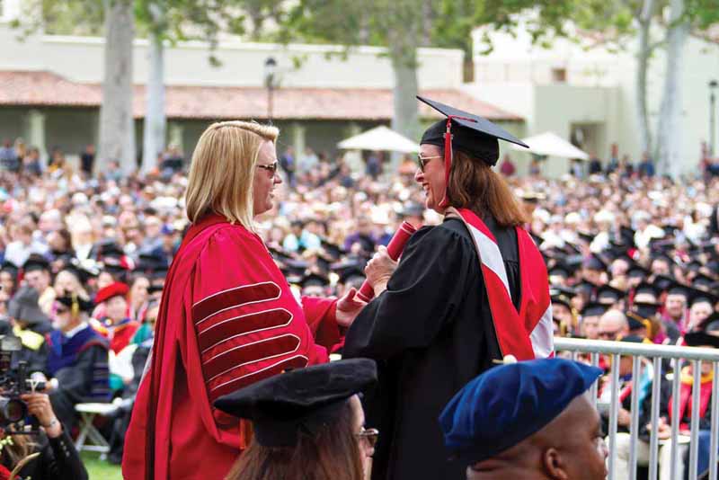 President Erika Beck shakes a graduate's hand during spring commencement, 2018
