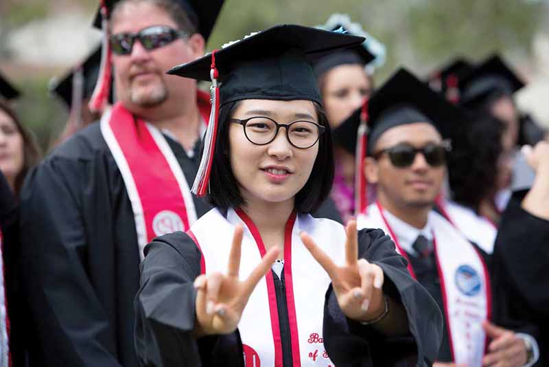 A student flashes the peace sign at the 2018 commencement