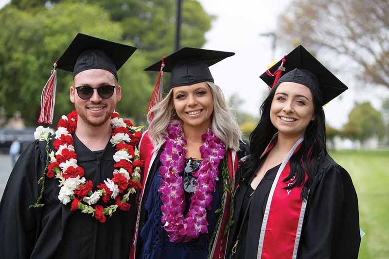 Three friends smile at the 2018 spring commencement