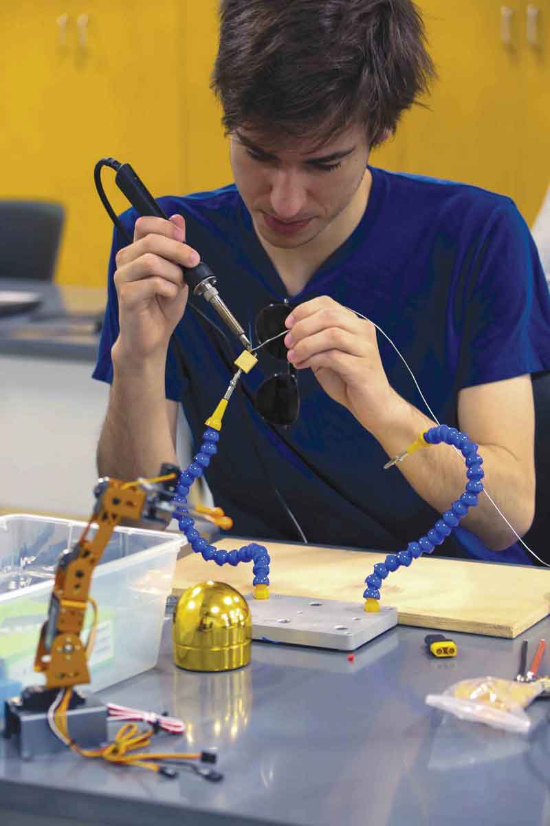 Mechatronics Engineering student Grant Kohne solders components for a robot. 