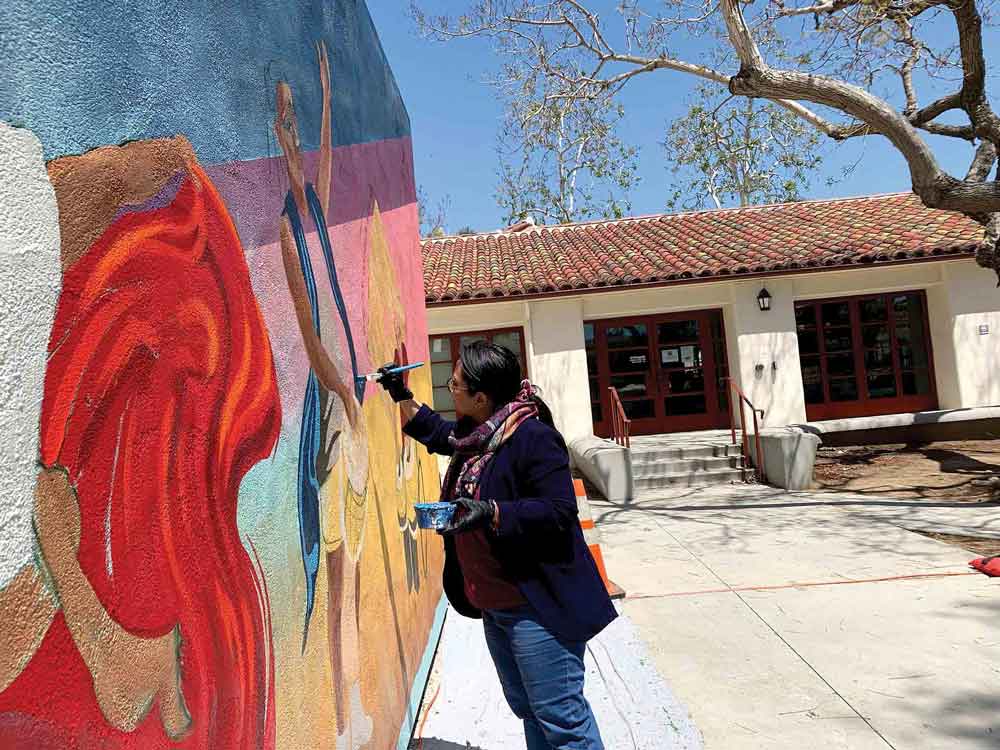 Caryl Ann Becerra helps paint details on the right side.