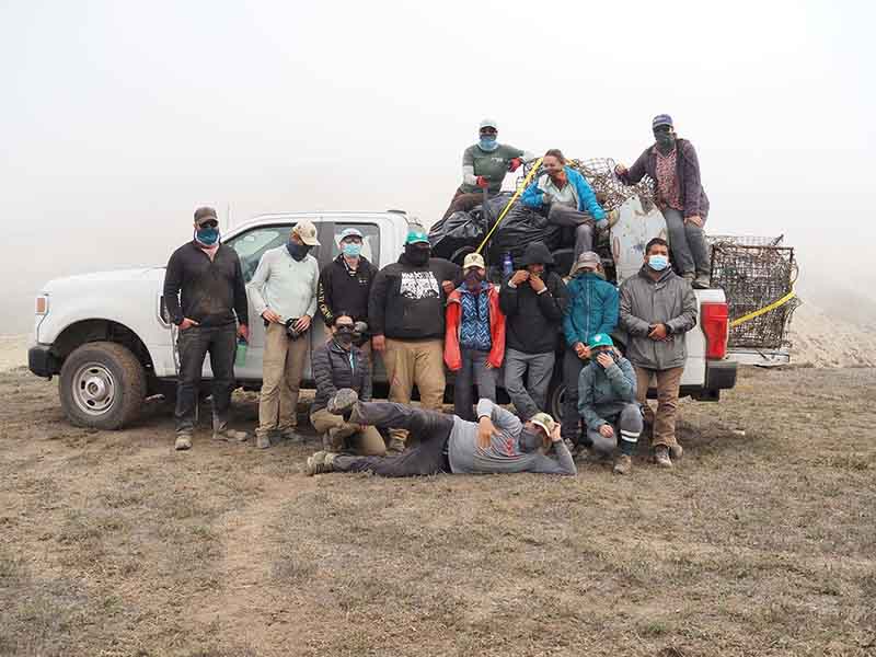 Group of student volunteers posing by a truck loaded with debris.