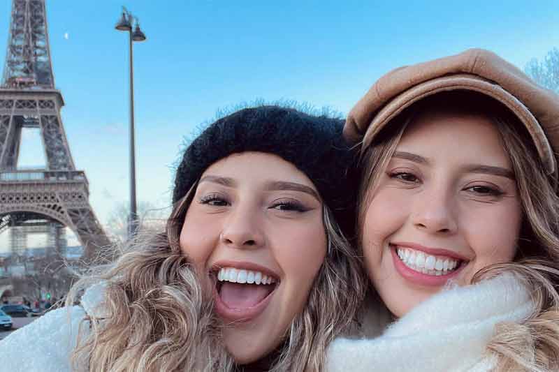 2 ladies smiling infront of the effiel tower